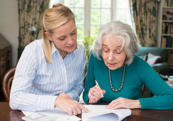 Woman Helping Senior Neighbor With Paperwork Woman Helping Senior Neighbor With Paperwork
